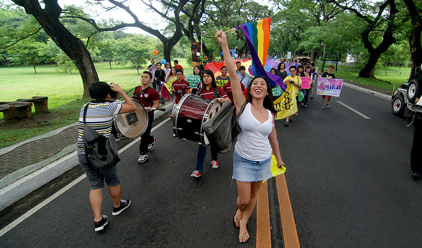 Photo in Philippines of activist Santy Layno leading a procession and waving the pride flag